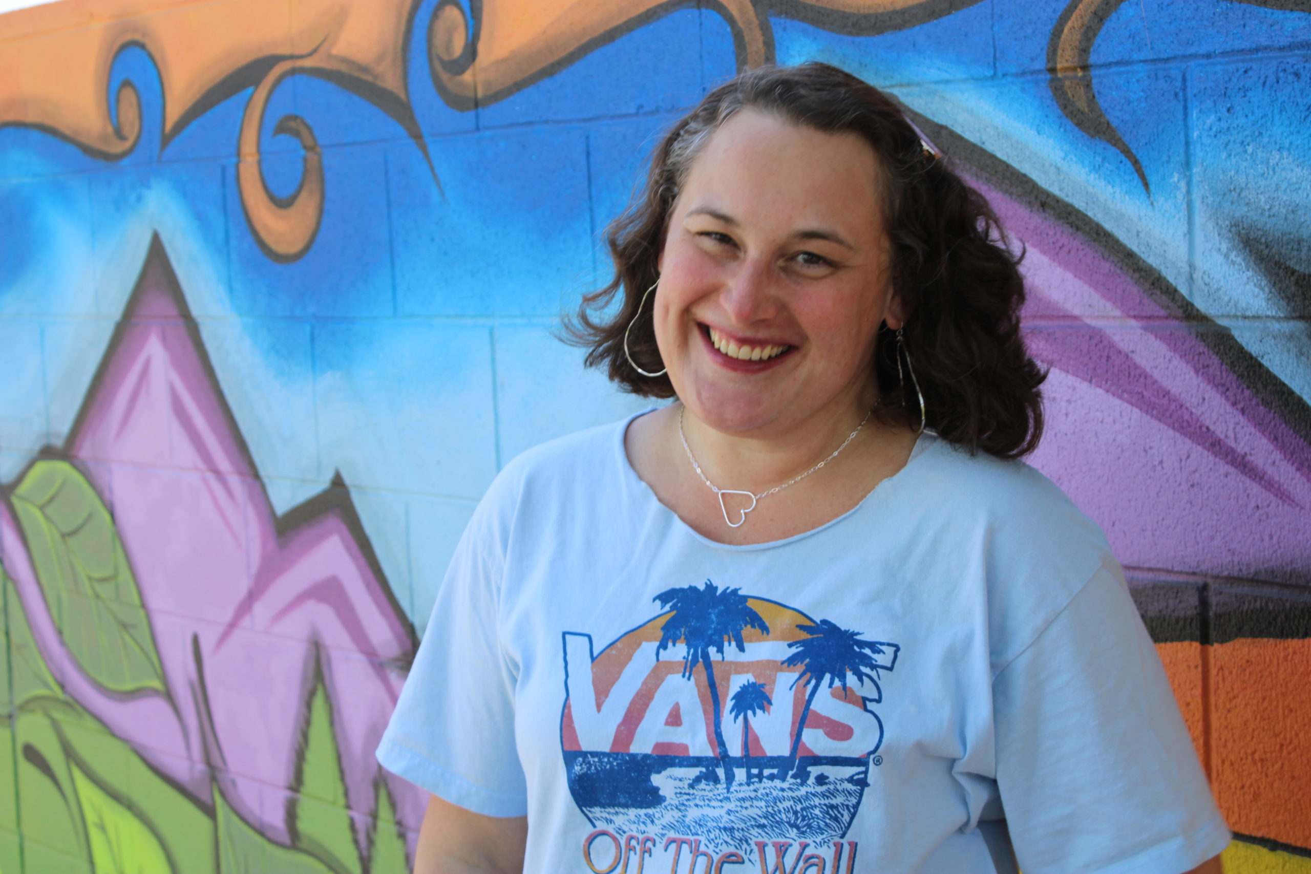 Heidi Parmenter smiling in front of a colorful mural at a community youth center.