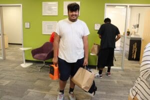 A teen holding backpack and a bag of school supplies